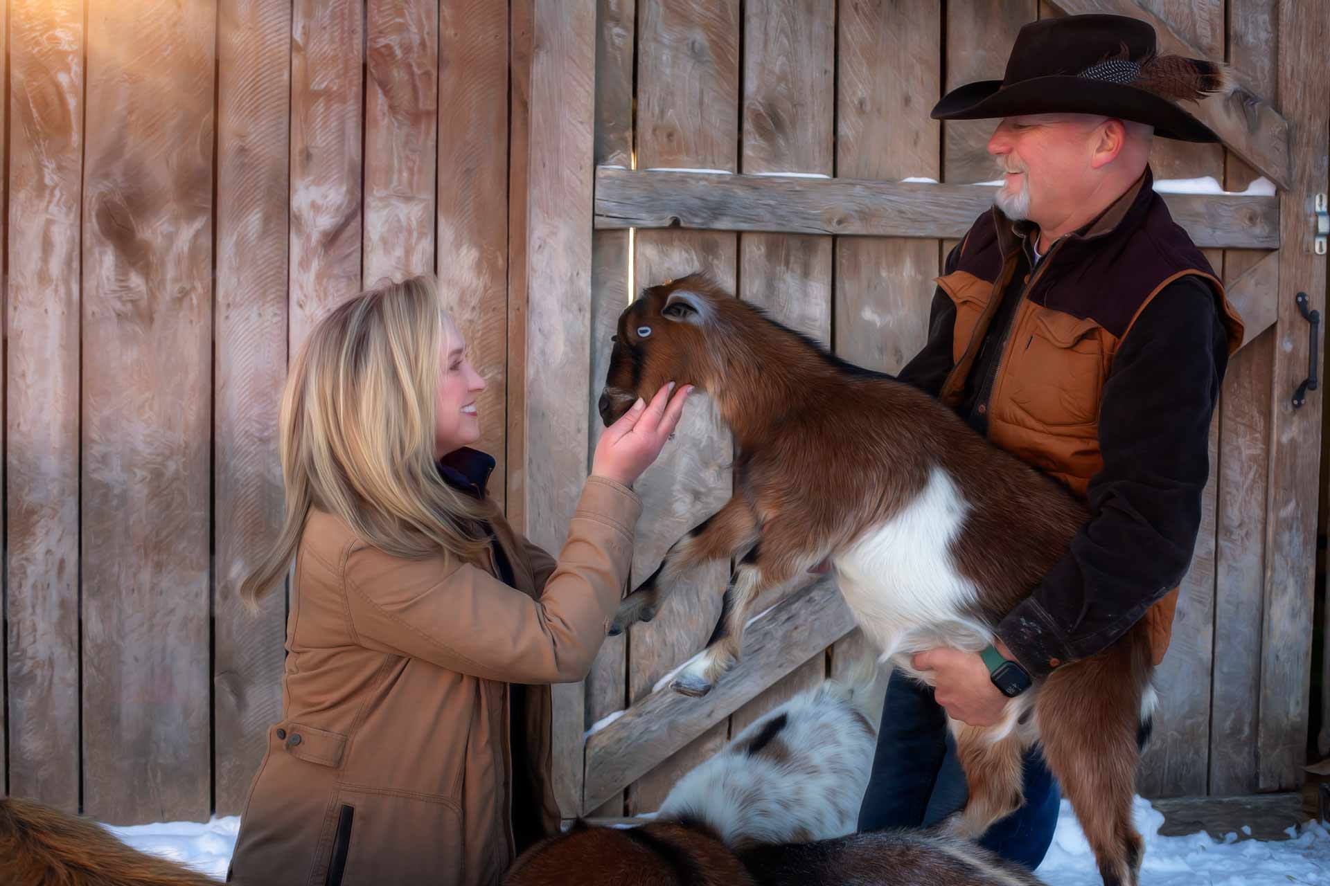 Husband and wife holding a goat during professional photography session at Moments By T Franklin Tennessee