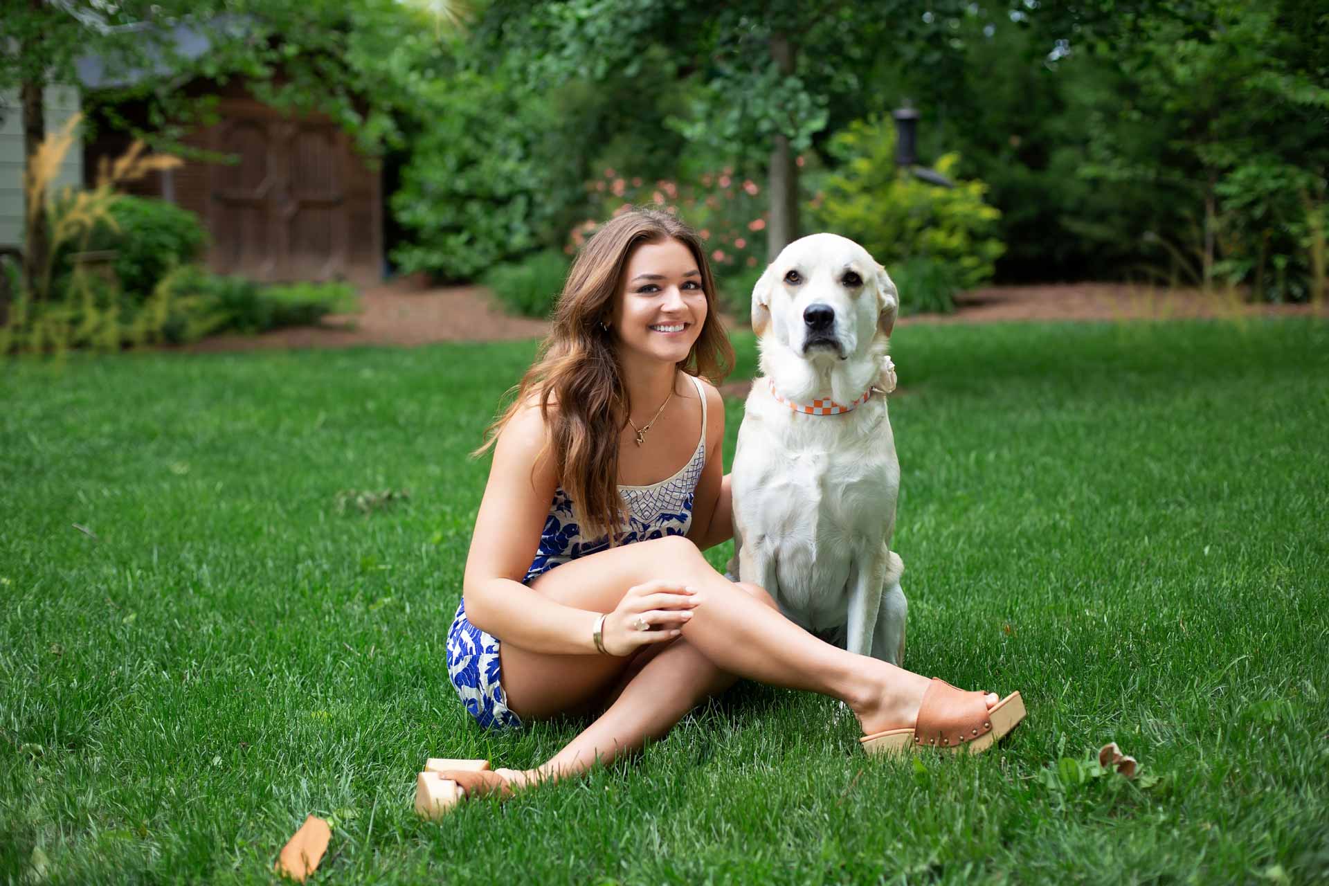 High School Senior girl sitting on the grass with her white lab dog during a professional senior photography session at Moments By T, Franklin Tennessee