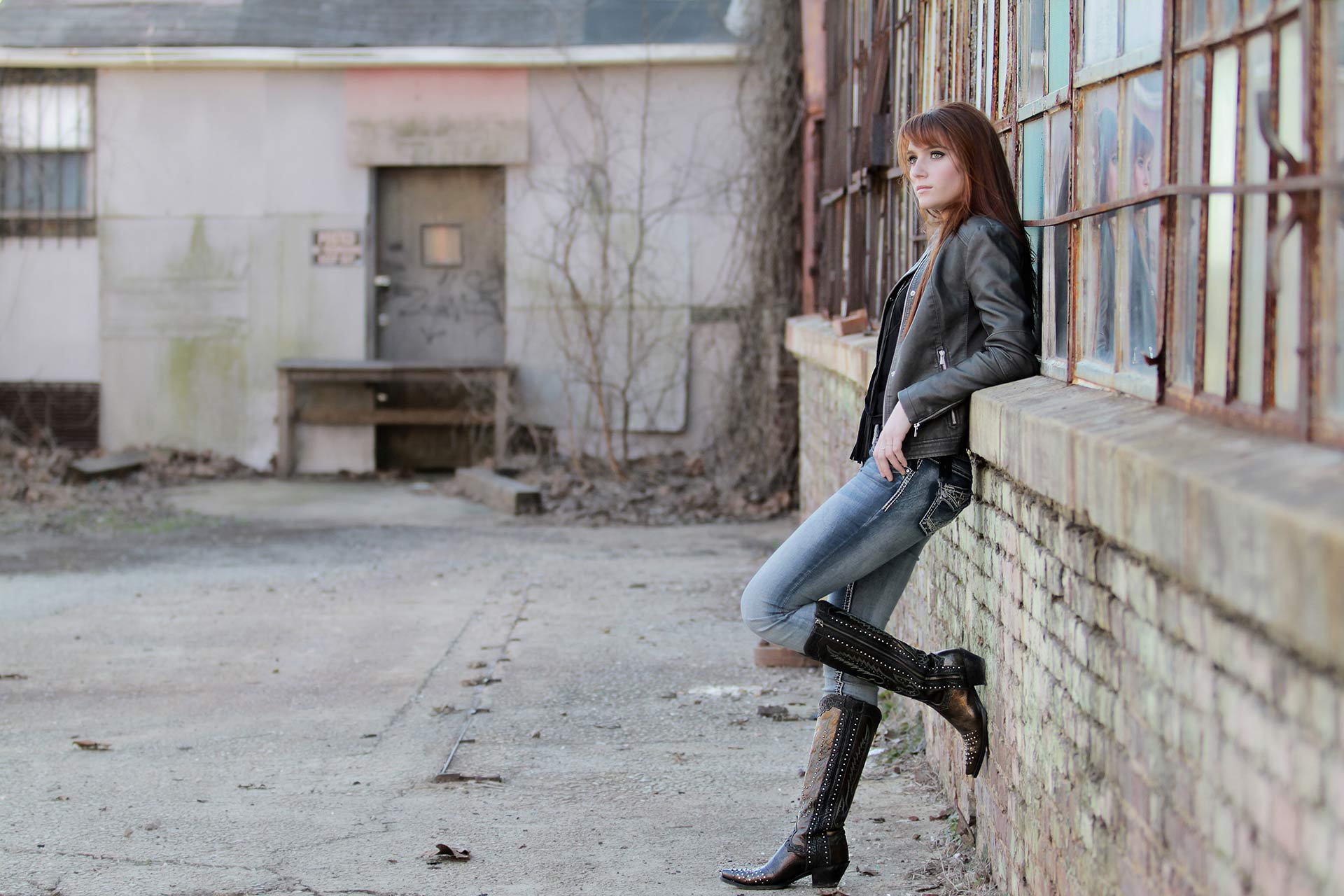 Teen girl resting against an old abandoned building during a professional senior photography session at Moments By T, Franklin Tennessee