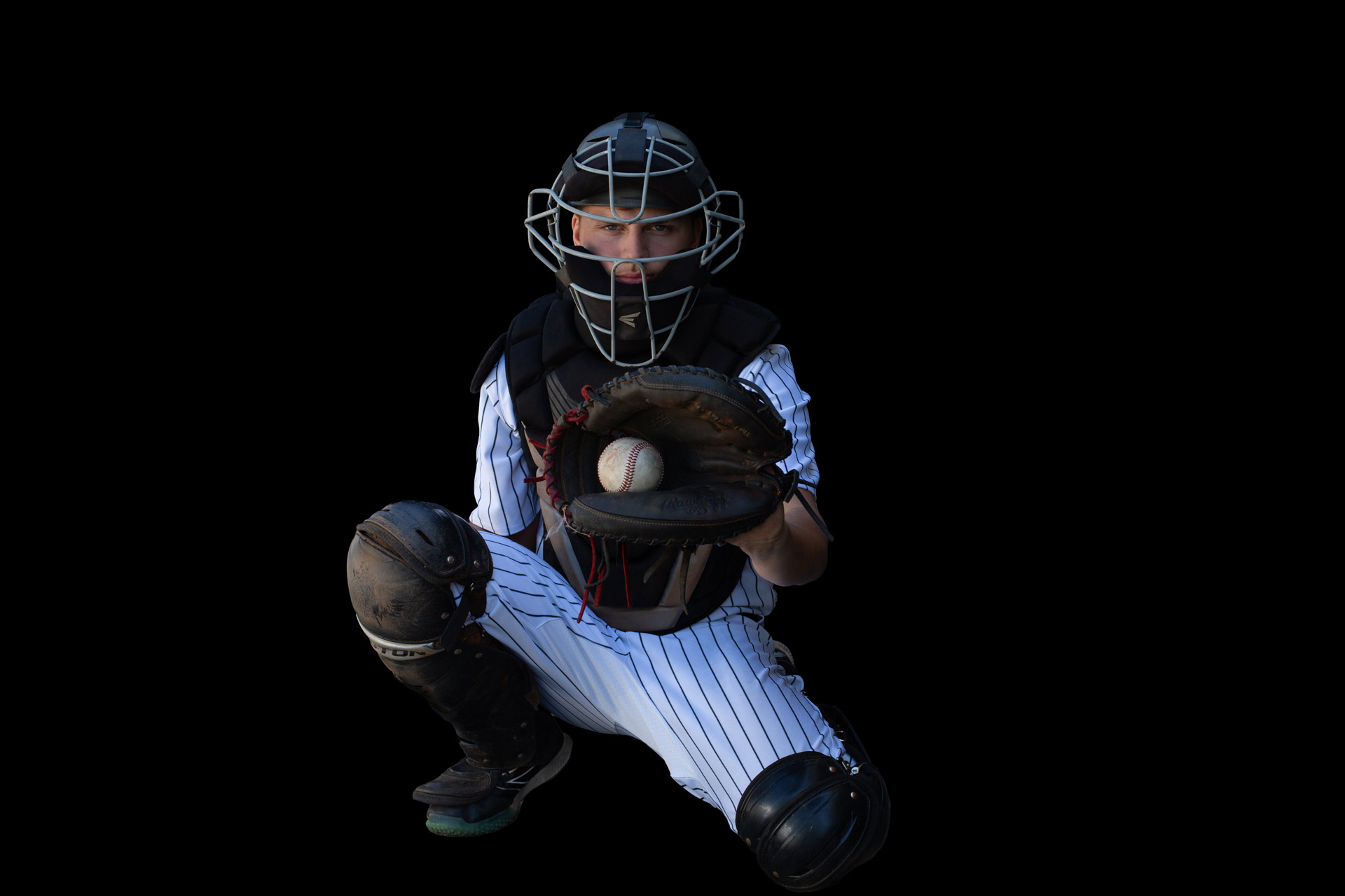Baseball catcher posing in the catchers position with a ball in the mitt during a professional high school senior photography session at Moments By T, Franklin Tennessee